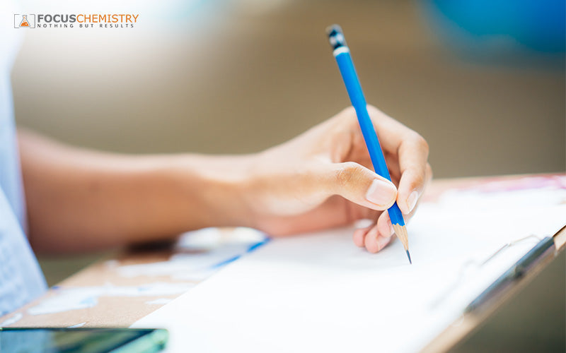 Student writing notes while practicing Chemistry model answer techniques.